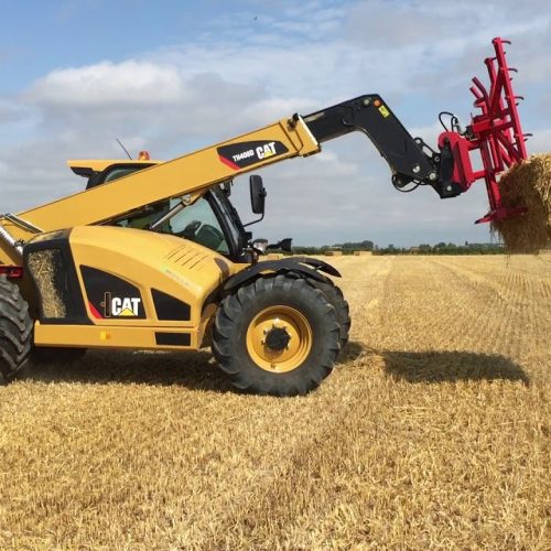 Telehandler CAT TH 408D lifting hay cubes on field