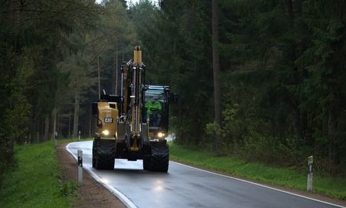 Wheel Excavator CAT M315F with flash lights on wet street