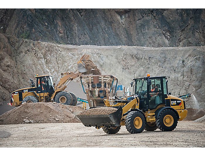 Compact wheel loader CAT 908M transporting sand at jobsite
